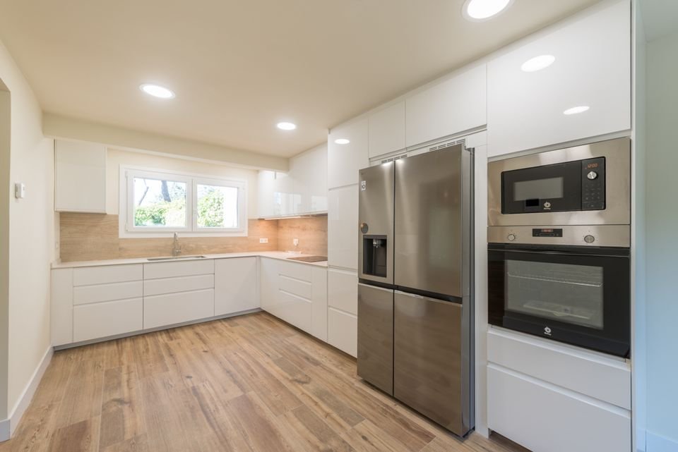 Cocina en blanco con ventana al jardín