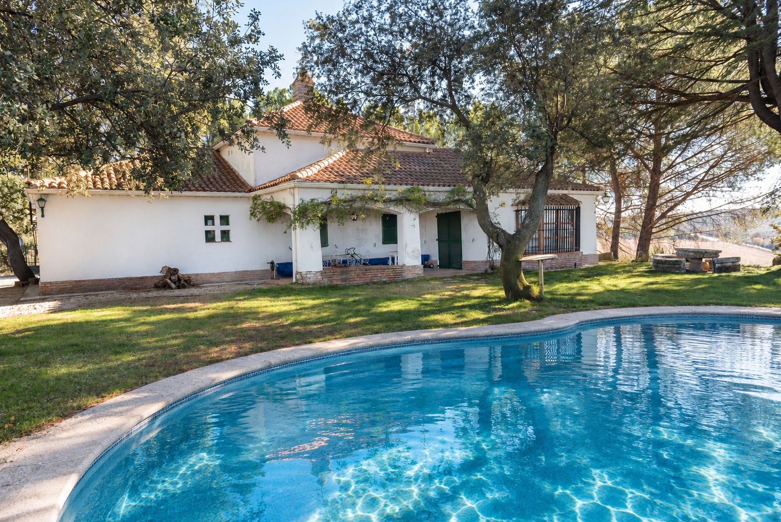 La casa blanca junto a la piscina, en lo alto de la loma
