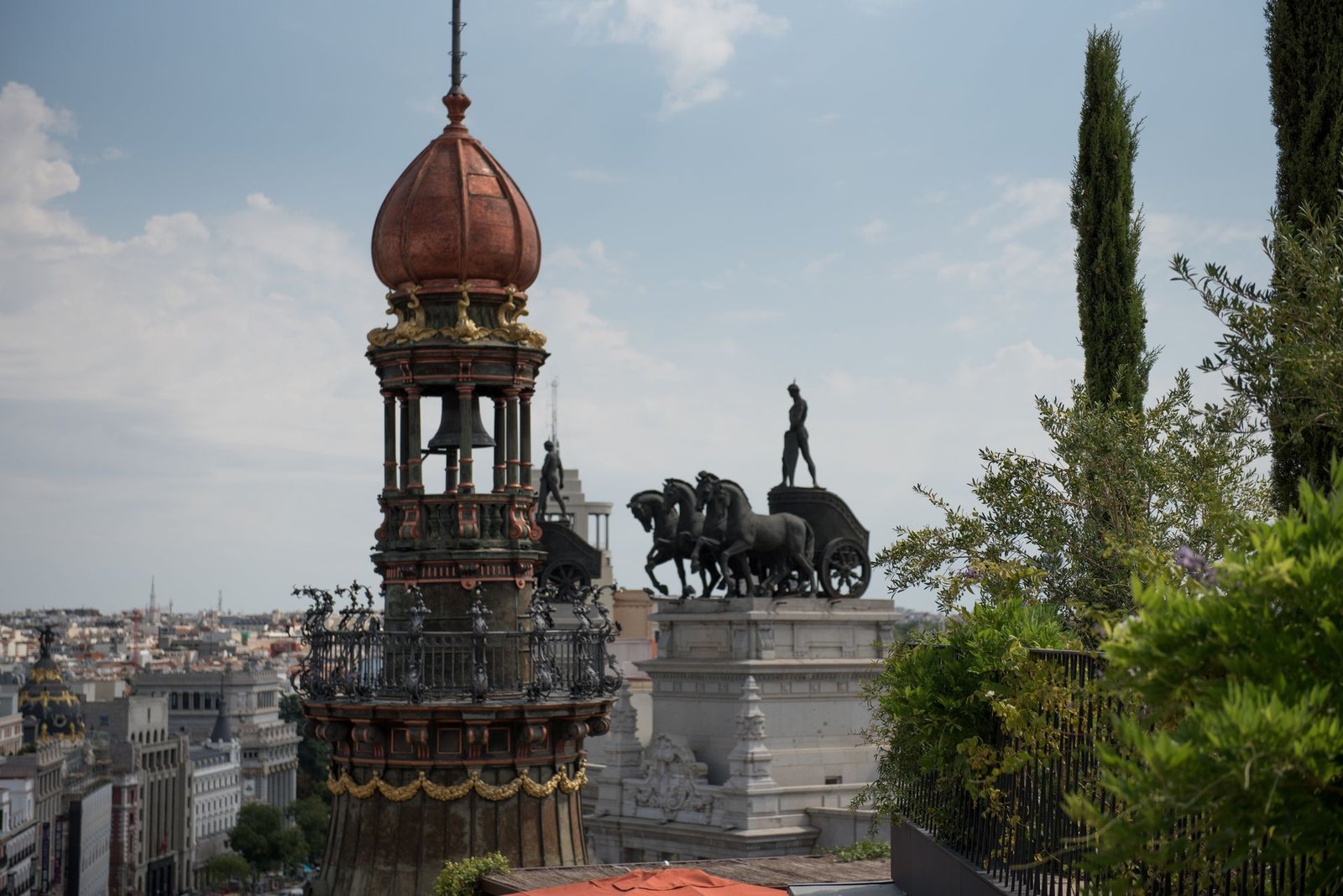Cúpula de cobre y cuadriga sobre los tejados de Madrid, desde una azotea con jardín